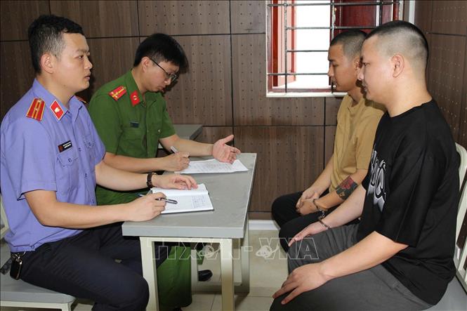 Cơ quan chức năng lấy lời khai các đối tượng trong đường dây tội phạm lừa đảo xuyên quốc gia. Ảnh: TTXVN phát