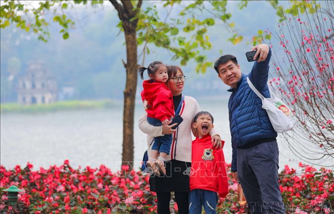 Cả gia đình cùng nhau ghi lại khoảnh khắc của mùa Xuân bên hồ Gươm (1/2023). Ảnh: Thanh Tùng – TTXVN