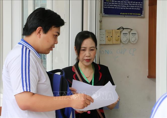 Thí sinh tại điểm thi Trường THPT Long Xuyên (thành phố Long Xuyên) được giám thị gọi vào phòng thi làm thủ tục. Ảnh: Công Mạo-TTXVN