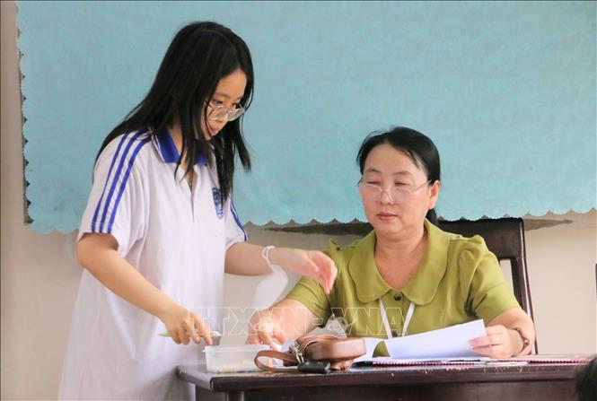Thí sinh tại điểm thi Trường THPT Long Xuyên đối chiếu thông tin cá nhân và nhận giấy báo dự thi. Ảnh: Công Mạo-TTXVN