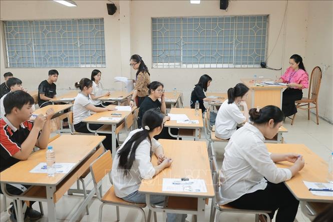 Giám thị phát giấy thi cho thí sinh. Ảnh: Minh Quyết - TTXVN