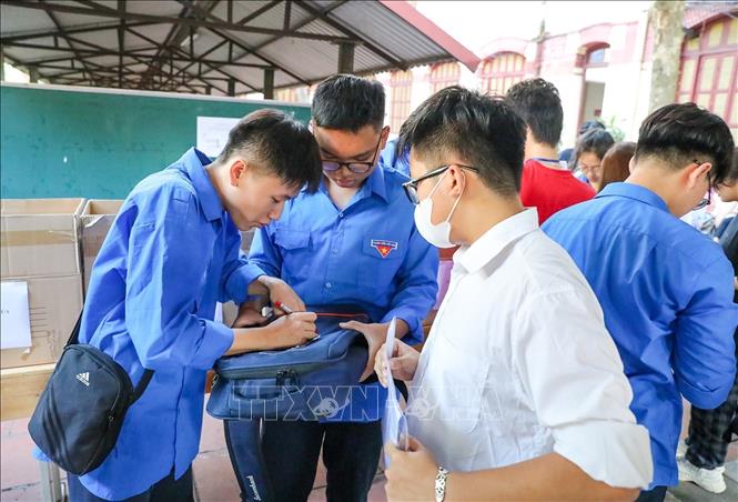 Thanh niên tình nguyện hỗ trợ thí sinh gửi đồ bên ngoài phòng thi tại điểm trường THPT Trần Phú (quận Hoàn Kiếm). Ảnh: Khánh Hoà - TTXVN