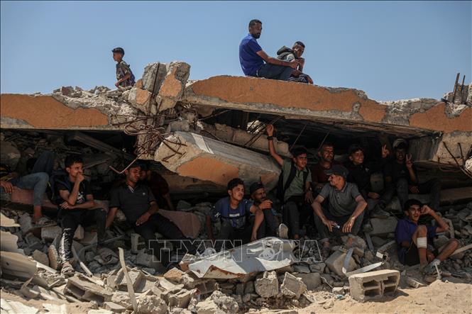 Người dân Palestine ngồi trên đống đổ nát ở khu vực Sudaniya, phía Bắc thành phố Gaza. Ảnh: THX/TTXVN