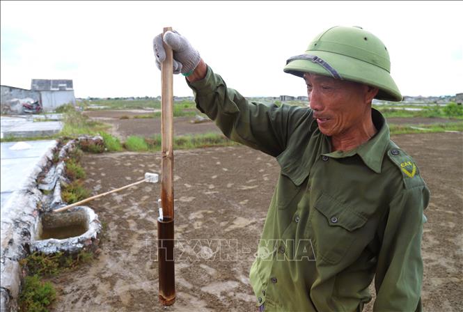 Đo độ mặn của nước tinh chất sau quá trình lọc lấy nước mặn để có lượng nước có độc mặn phù hợp trước khi phơi lấy muối thành phẩm. Ảnh: Xuân Tiến-TTXVN 