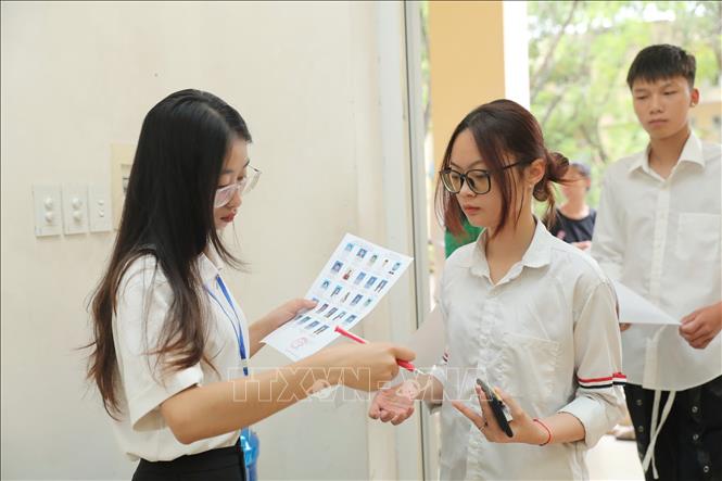 Giám thị gọi thí sinh vào phòng thi tại điểm thi Trường THPT Nguyễn Gia Thiều (Long Biên, Hà Nội). Ảnh: Thành Phương - TTXVN
