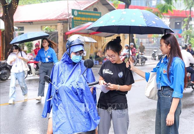 Thanh niên tình nguyện hỗ trợ thí sinh che mưa vào địa điểm thi trường THPT chuyên Chu Văn An (quận Tây Hồ, Hà Nội). Ảnh: Khánh Hoà - TTXVN