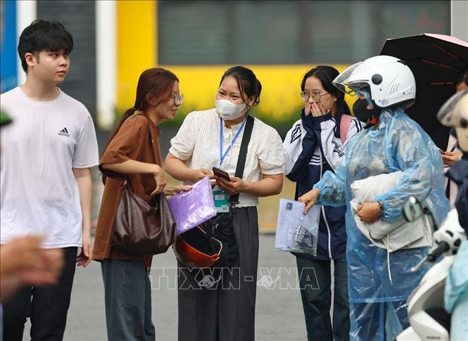 Thí sinh và người nhà trao đổi về đề thi cùng phóng viên. Ảnh: Thanh Tùng - TTXVN