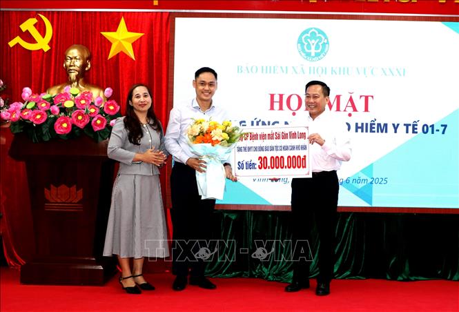 Đại diện doanh nghiệp trao tặng kinh phí hỗ trợ mua thẻ bảo hiểm y tế cho người có hoàn cảnh khó khăn. Ảnh: Lê Thúy Hằng - TTXVN