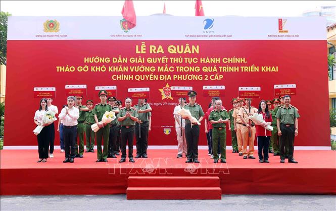 Trung tướng Nguyễn Thanh Tùng, Giám đốc Công an thành phố Hà Nội và Đại tá Ngô Như Cường, Phó Cục trưởng Cục cảnh sát quản lý hành chính về trật tự xã hội tặng hoa chúc mừng 8 tổ công tác triển khai tại cơ sở ra mắt tại buổi lễ. Ảnh: Phạm Kiên - TTXVN