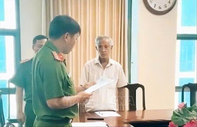 Cơ quan Cảnh sát điều tra tiến hành tống đạt quyết định tố tụng đối với Ngô Chí Hiếu (áo trắng), Giám đốc Công ty TNHH du lịch Mỹ Thuận về hành vi “Mua bán trái phép hóa đơn” và “Làm giả tài liệu của cơ quan, tổ chức”. Ảnh: TTXVN phát