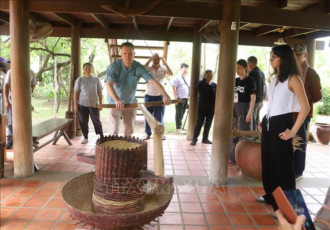 Du khách thích thú trải nghiệm hoạt động xay lúa truyền thống của người dân bản địa tại Làng hữu cơ Patom, tỉnh Nakhon Pathom. Ảnh: Đỗ Sinh - PV TTXVN tại Thái Lan