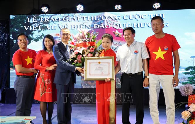 Đại sứ Vũ Quang Minh trao Giấy khen và tặng hoa cho bà Bùi Thị Thu Minh, Trưởng ban liên lạc người Việt tại châu Âu “Vì biển đảo Việt Nam”, Chủ tịch CLB Trường Sa tại CHLB Đức. Ảnh: Thu Hằng-PV TTXVN tại Đức
