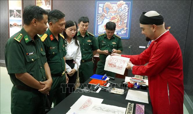 Các đại biểu tìm hiểu về in tranh tại Triển lãm. Ảnh: Lê Phước Ngọc - TTXVN
