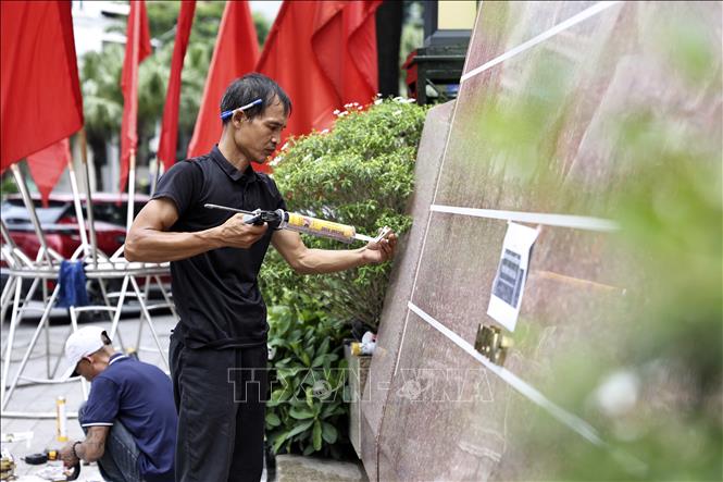 Công nhân đơn vị thi công gắn biển trụ sở phường Ngọc Hà, thành phố Hà Nội. Ảnh: Lê Đông - TTXVN