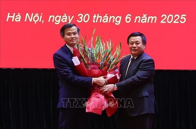 Ủy viên Bộ Chính trị, Giám đốc Học viện Chính trị quốc gia Hồ Chí Minh, Chủ tịch Hội đồng Lý luận Trung ương Nguyễn Xuân Thắng trao Quyết định và tặng hoa chúc mừng ông Đoàn Minh Huấn. Ảnh: Văn Điệp – TTXVN