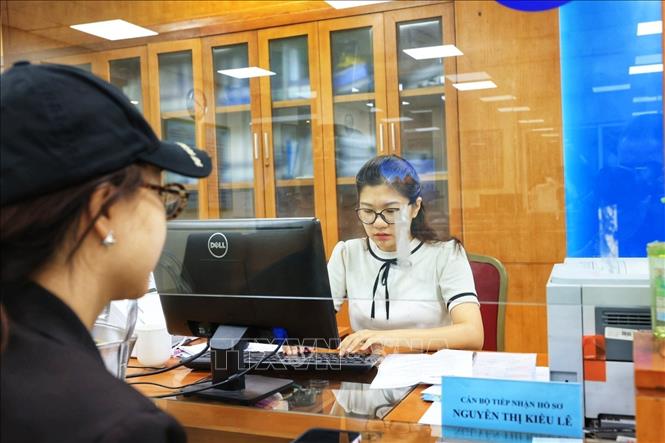 Cán bộ Trung tâm phục vụ hành chính công phường Hoàn Kiếm làm thủ tục hành chính cho người dân sáng 1/7. Ảnh: Tuấn Anh  - TTXVN 