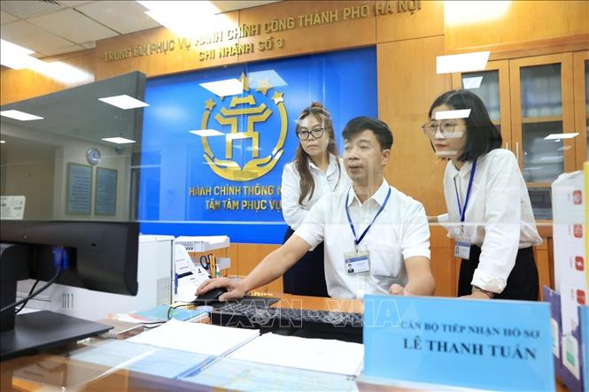 Cán bộ Trung tâm phục vụ hành chính công phường Hoàn Kiếm làm thủ tục hành chính cho người dân sáng 1/7. Ảnh: Tuấn Anh  - TTXVN 