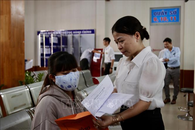 Công chức, viên chức Trung tâm hành chính công phường Linh Xuân, Thành phố Hồ Chí Minh hướng dẫn người dân làm thủ tục trong ngày làm việc đầu tiên. Ảnh: Thanh Vũ-TTXVN 