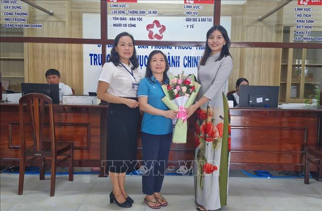 Cán bộ phường Phước Thắng, Thành phố Hồ Chí Minh tặng hoa cho người dân đến làm thủ tục hành chính đầu tiên trong ngày 1/7. Ảnh: Hoàng Nhị - TTXVN