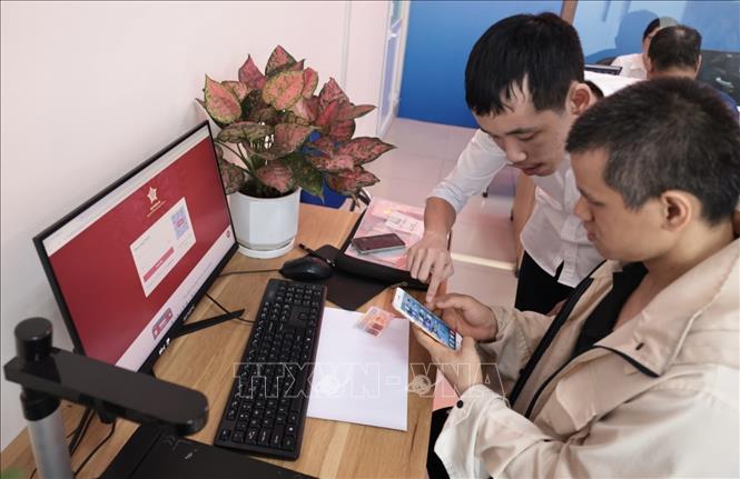 Cán bộ bộ phận phục vụ hành chính công UBND phường Hoàng Mai hướng dẫn người dân thực hiện thủ tục hành chính online. Ảnh: Trần Việt - TTXVN 