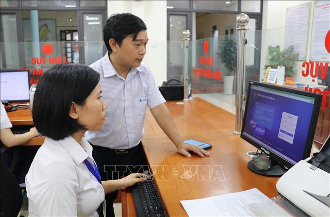 Cán bộ Trung tâm Công nghệ thông tin viễn thông Ninh Bình hướng dẫn cán bộ, công chức, viên chức phường Tây Hoa Lư, tỉnh Ninh Bình thực hiện các phần mềm. Ảnh: Thùy Dung - TTXVN