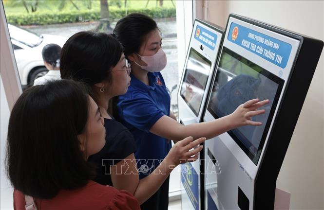 Người dân phường Hoàng Mai đến làm thủ tục hành chính tại UBND phường được hướng dẫn lấy số. Ảnh: Trần Việt - TTXVN 