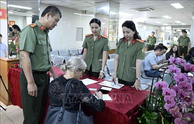 Cán bộ, chiến sĩ Cục quản lý xuất nhập cảnh, Bộ Công an hướng dẫn người nước ngoài làm thủ tục cấp tài khoản định danh điện tử. Ảnh: Phạm Kiên - TTXVN