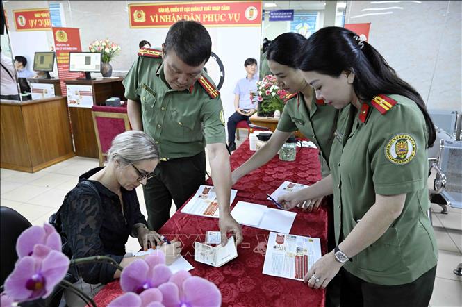 Cán bộ, chiến sĩ Cục quản lý xuất nhập cảnh, Bộ Công an hướng dẫn người nước ngoài làm thủ tục cấp tài khoản định danh điện tử. Ảnh: Phạm Kiên - TTXVN