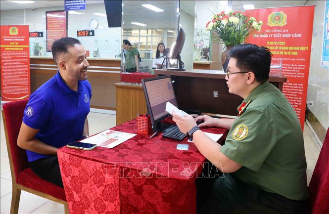 Cán bộ, chiến sĩ Cục quản lý xuất nhập cảnh, Bộ Công an hướng dẫn người nước ngoài cư trú tại Việt Nam làm thủ tục cấp tài khoản định danh điện tử. Ảnh: Phạm Kiên - TTXVN