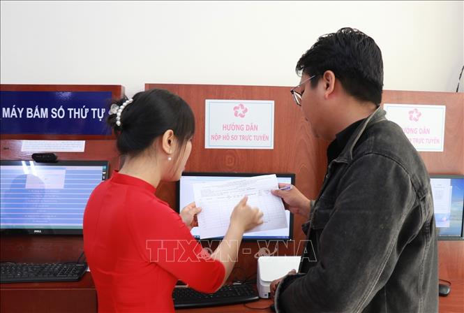 Cán bộ bán chuyên trách hướng dẫn người dân các thủ tục lấy số, ghi biểu mẫu tại trung tâm hành chính công phường Nha Trang, tỉnh Khánh Hòa trong ngày làm việc đầu tiên 1/7. Ảnh: Phan Sáu - TTXVN