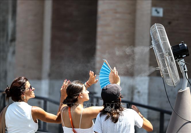 Khách du lịch làm mát trước quạt phun sương công cộng tại Rome, Italy ngày 27/6/2025. Ảnh: THX/TTXVN