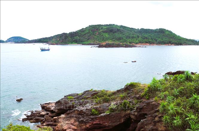 Khung cảnh cửa biển Lạch Quèn (xã Quỳnh Phú) nhìn từ khu vực lưng núi hang trâu Mành Sơn. Có thể thầy rõ rải đá nằm chếch cửa lạch và dãy núi Bàn Cờ phía xa xa. Ảnh: Xuân Tiến -TTXVN 