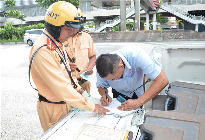 Cảnh sát giao thông lập biên bản một trường hợp tài xế xe khách vi phạm. Ảnh: Linh Sơn –TTXVN