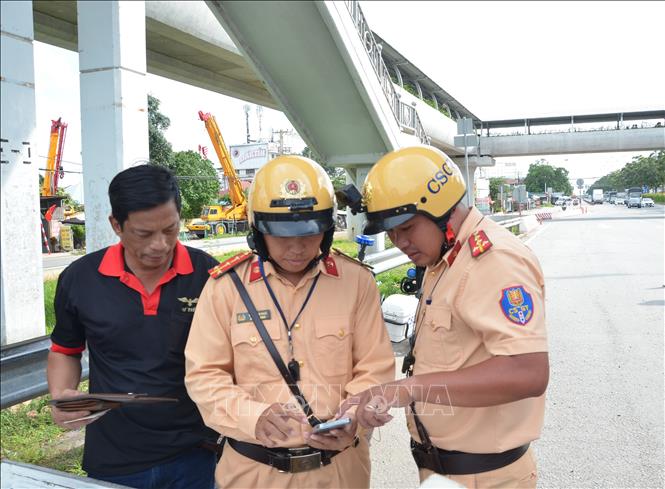 Cảnh sát giao thông kiểm tra thiết bị giám sát camera hành trình qua điện thoại của tài xế xe khách. Ảnh: Linh Sơn –TTXVN