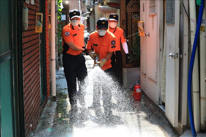 Nhân viên cứu hộ phun nước tại một khu dân cư ở Seoul, Hàn Quốc, trong đợt nắng nóng gay gắt. Ảnh: Yonhap/TTXVN
