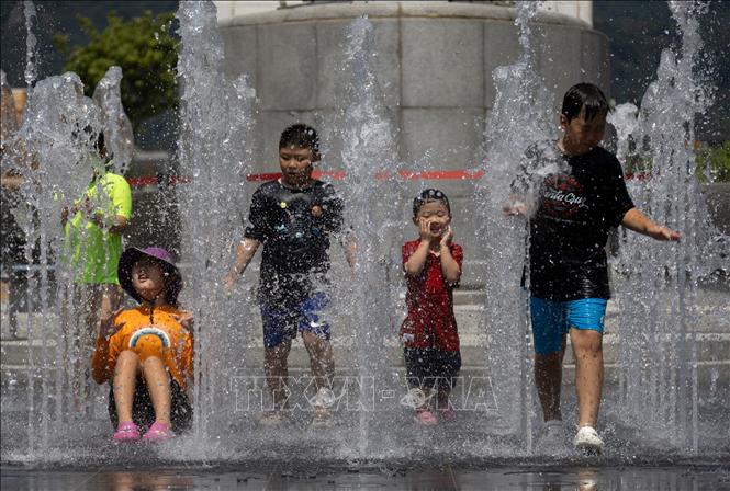 Các em nhỏ chơi đùa bên đài phun nước để tránh nóng, tại Seoul, Hàn Quốc. Ảnh: THX/TTXVN