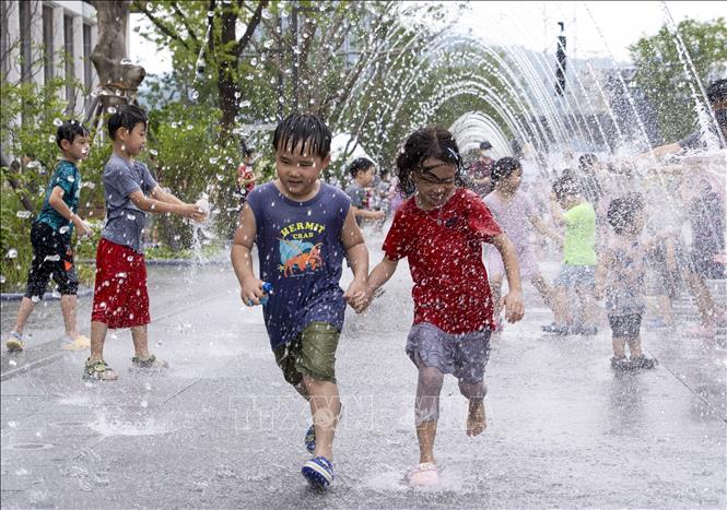 Các em nhỏ chơi đùa bên đài phun nước để tránh nóng, tại Seoul, Hàn Quốc. Ảnh: THX/TTXVN