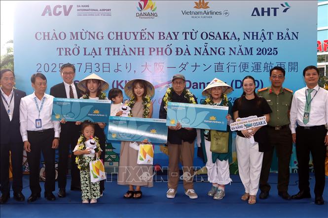 Ban Tổ chức tặng hoa, quà cho ba vị khách may mắn trên chuyến bay từ Osaka đến Đà Nẵng tại lễ đón. Ảnh: Trần Lê Lâm - TTXVN 