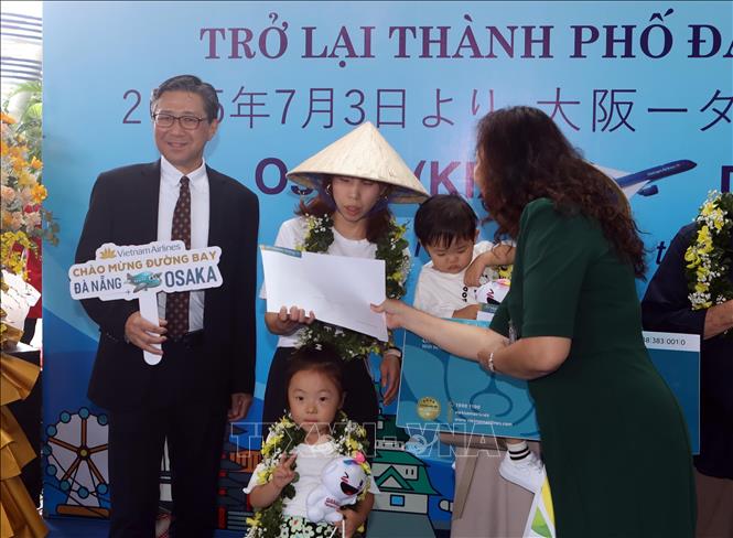 Ban Tổ chức tặng hoa, quà cho ba vị khách may mắn trên chuyến bay từ Osaka đến Đà Nẵng tại lễ đón. Ảnh: Trần Lê Lâm - TTXVN 
