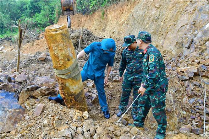 Lực lượng chức năng di dời quả bom đến nơi hủy nổ. Ảnh: TTXVN phát