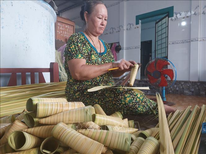 Bà Đoàn Thị Bé thắt ống lá dừa để làm bánh Dừa Giồng Luông. Ảnh: Chương Đài  - TTXVN 
