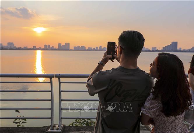 Các bạn trẻ lưu lại khoảnh khắc với vẻ đẹp của hoàng hôn Hồ Tây. Ảnh: Khánh Hòa - TTXVN