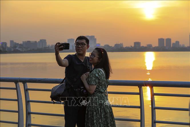 Các bạn trẻ lưu lại khoảnh khắc với vẻ đẹp của hoàng hôn Hồ Tây. Ảnh: Khánh Hòa - TTXVN