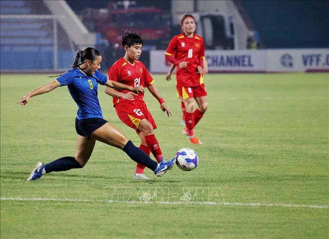 Pha tranh bóng giữa Ngân Thị Vạn Sự (số 21, áo đỏ) với Lexi Taitague (số 8, áo lam, Guam). Ảnh: Phạm Hậu - TTXVN