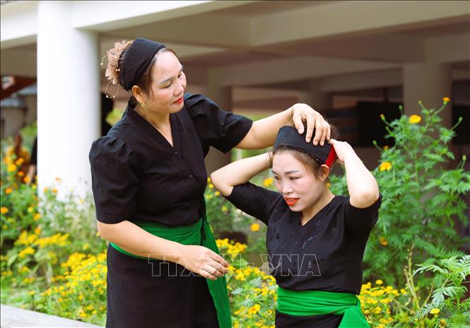 Chị em phụ nữ dân tộc Ơ Đu ở bản tái định cư Văng Môn (xã Nga My, Nghệ An) giúp nhau mặc trang phục truyền thống để cùng bà con dân bản đi dự lễ tiếng đón tiếng sấm đầu năm. Ảnh: Xuân Tiến - TTXVN 