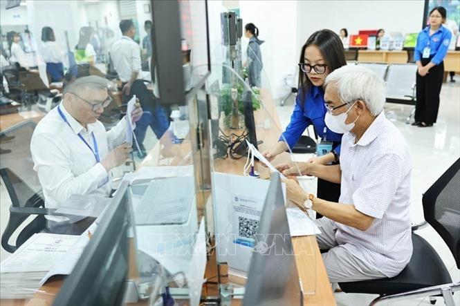 Đội thanh niên tình nguyện hỗ trợ vận hành chính quyền 2 cấp và cung cấp dịch vụ công trực tuyến tại Trung tâm Phục vụ hành chính công phường Cầu Giấy. Ảnh: Minh Đức - TTXVN