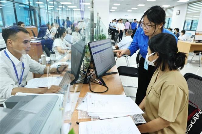 Đội thanh niên tình nguyện hỗ trợ vận hành chính quyền 2 cấp và cung cấp dịch vụ công trực tuyến tại Trung tâm Phục vụ hành chính công phường Cầu Giấy. Ảnh: Minh Đức - TTXVN