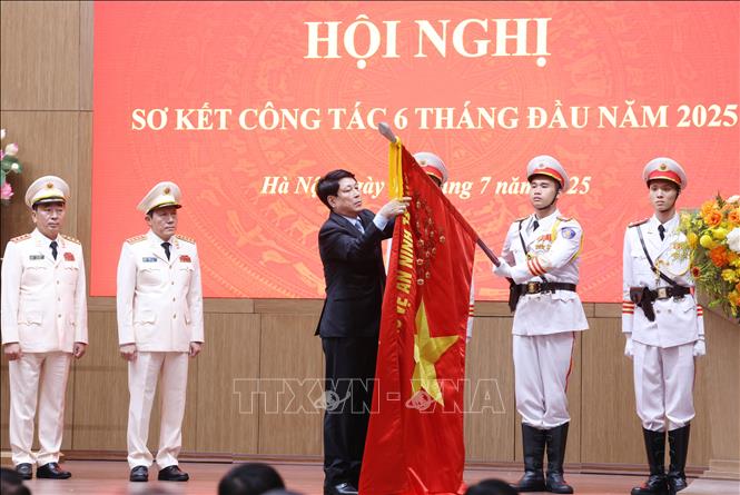 Chủ tịch nước Lương Cường gắn Huân chương Lao động hạng Ba lên lá cờ Quyết thắng của Bộ Công an. Ảnh: Lâm Khánh - TTXVN