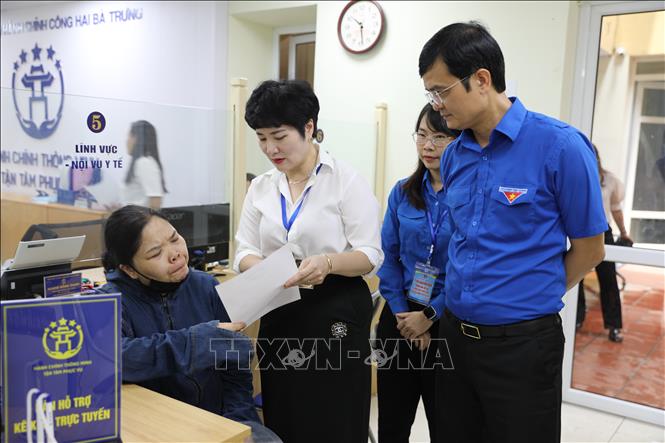 Cán bộ điểm phục vụ hành chính công hướng dẫn người dân làm thủ tục. Ảnh: Quốc Lũy - TTXVN