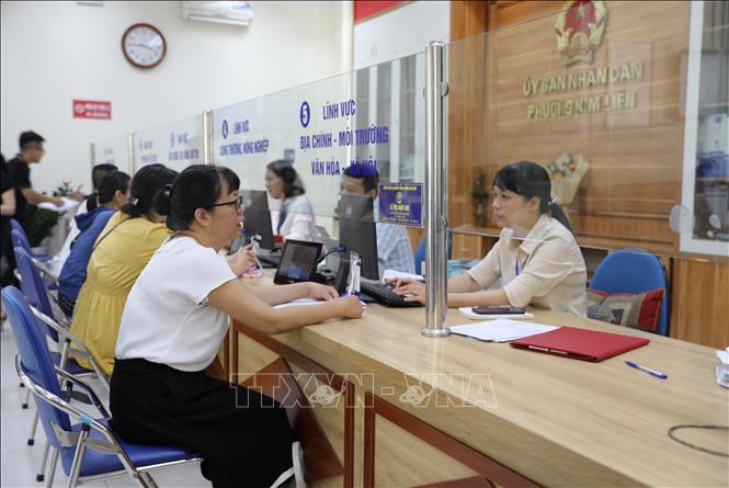 Cán bộ tại Điểm tiếp nhận, phục vụ hành chính công  phường Kim Liên tiếp nhận và xử lý thủ tục hành chính cho người dân. Ảnh: Quốc Lũy - TTXVN